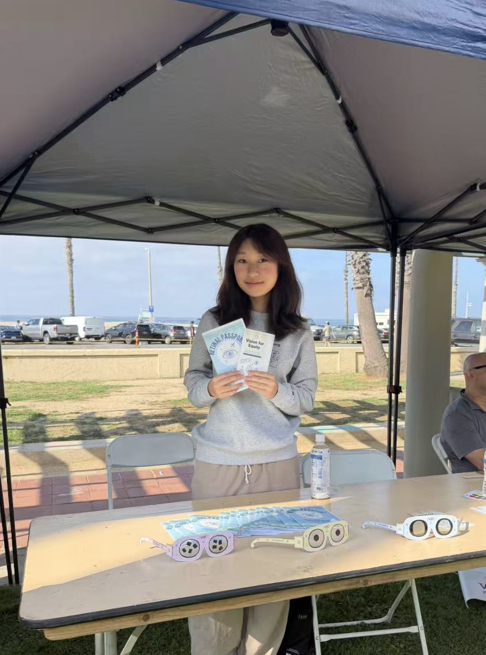 Vision for Equity representative holding retinal education materials at the event table